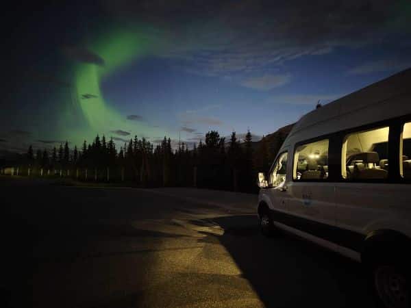 Guests stepping out of an Into the Wild Tours shuttle at Moraine Lake for a guided stargazing tour under the evening sky in Banff National Park, Canada.