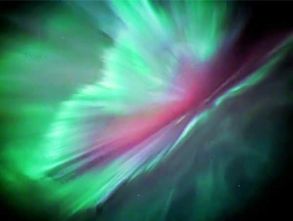 Northern lights with green and pink aurora dancing over Banff National Park during an Into the Wild Tours stargazing tour.