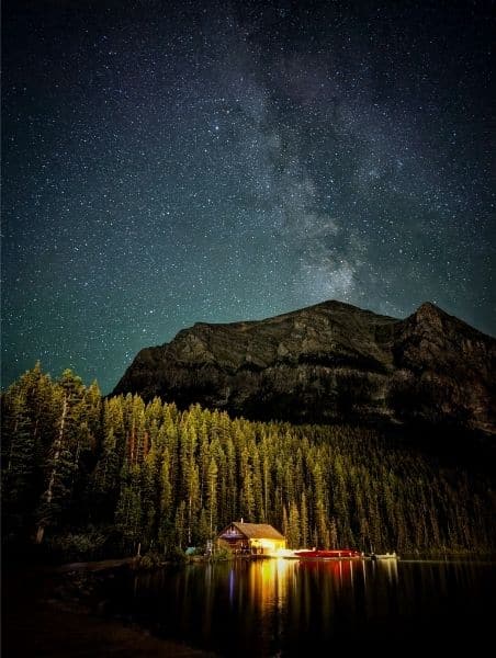 Starlit sky over Emerald Lake Lodge in Yoho National Park, featuring the Milky Way galaxy. The scene captures the peaceful reflection of the lodge and surrounding trees, offering a serene stargazing experience