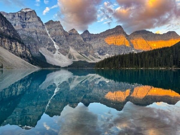 Sunrise over Moraine Lake with a perfect reflection of the Canadian Rockies mountains in the water at Banff National Park.