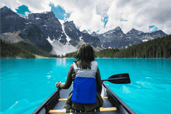 Canoeing on turquoise Moraine Lake surrounded by mountain peaks in Banff National Park