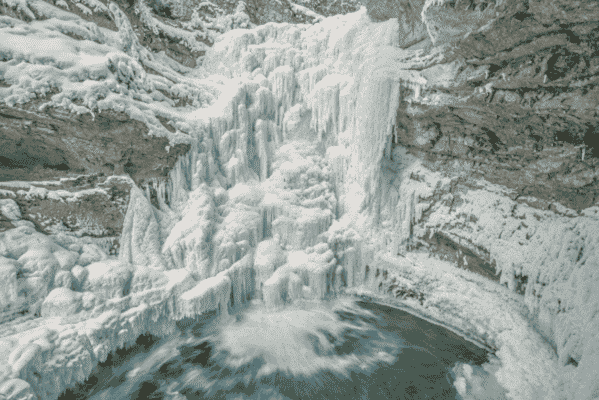 Frozen waterfall at Johnston Canyon in Banff National Park with icy formations and a turquoise pool below.