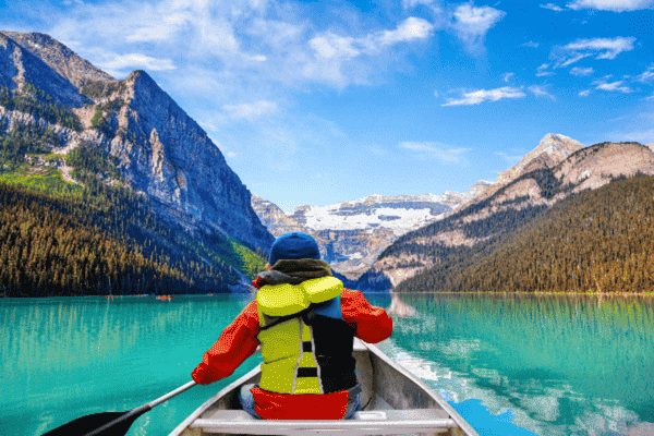 A stunning view of Lake Louise with clear turquoise water, surrounding mountains, and lush greenery. | Into the Wild Tours