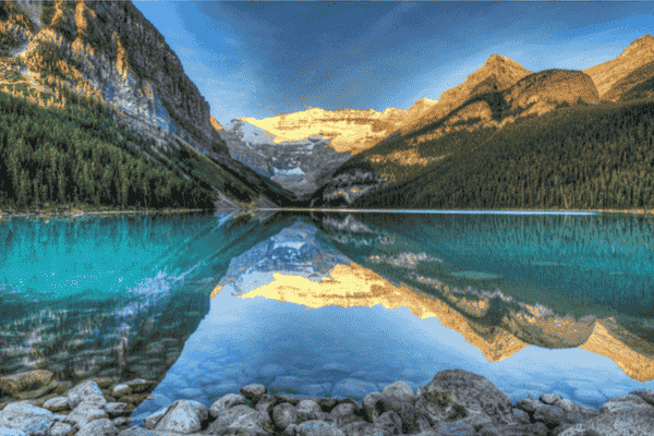 Turquoise waters of Lake Louise reflecting Victoria Glacier and surrounding Rocky Mountains at sunrise in Banff National Park.
