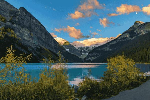 Lake Louise viewed from the shoreline trail with turquoise water, alpine forest, and snow-capped peaks in Banff National Park.